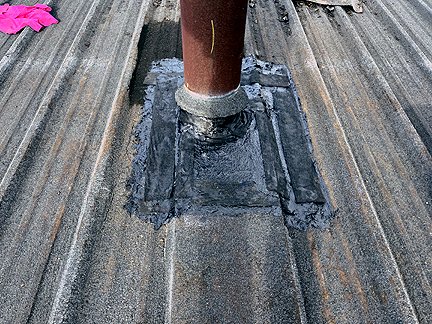 Pipe penetration in BUR Rolled Asphalt Modified Roof, has four voids at the base, with water pooled in the interior.